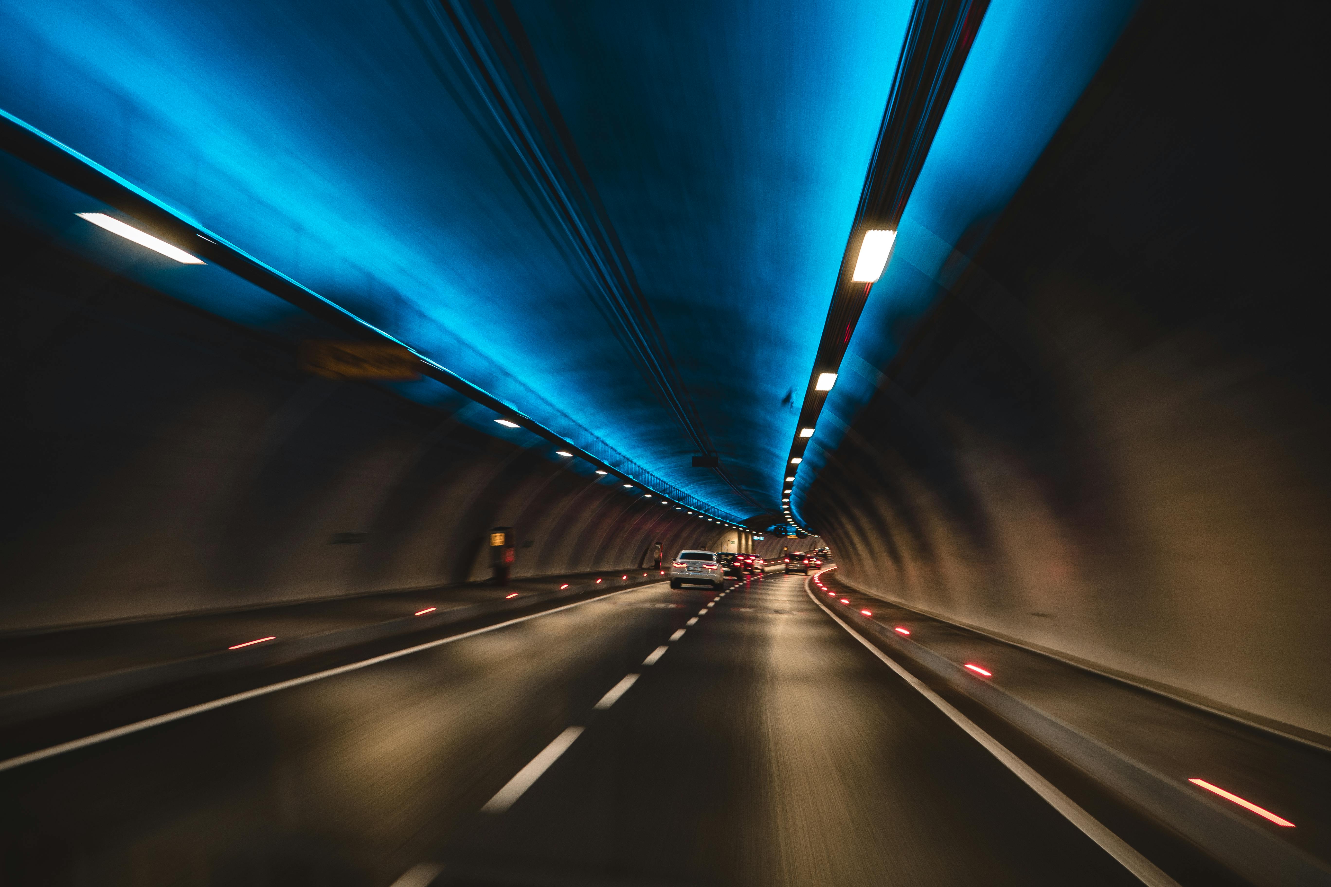 pexels-photo-1253049-1253049 Long exposure capture of cars driving through a modern tunnel with blue lighting, showcasing speed and motion.