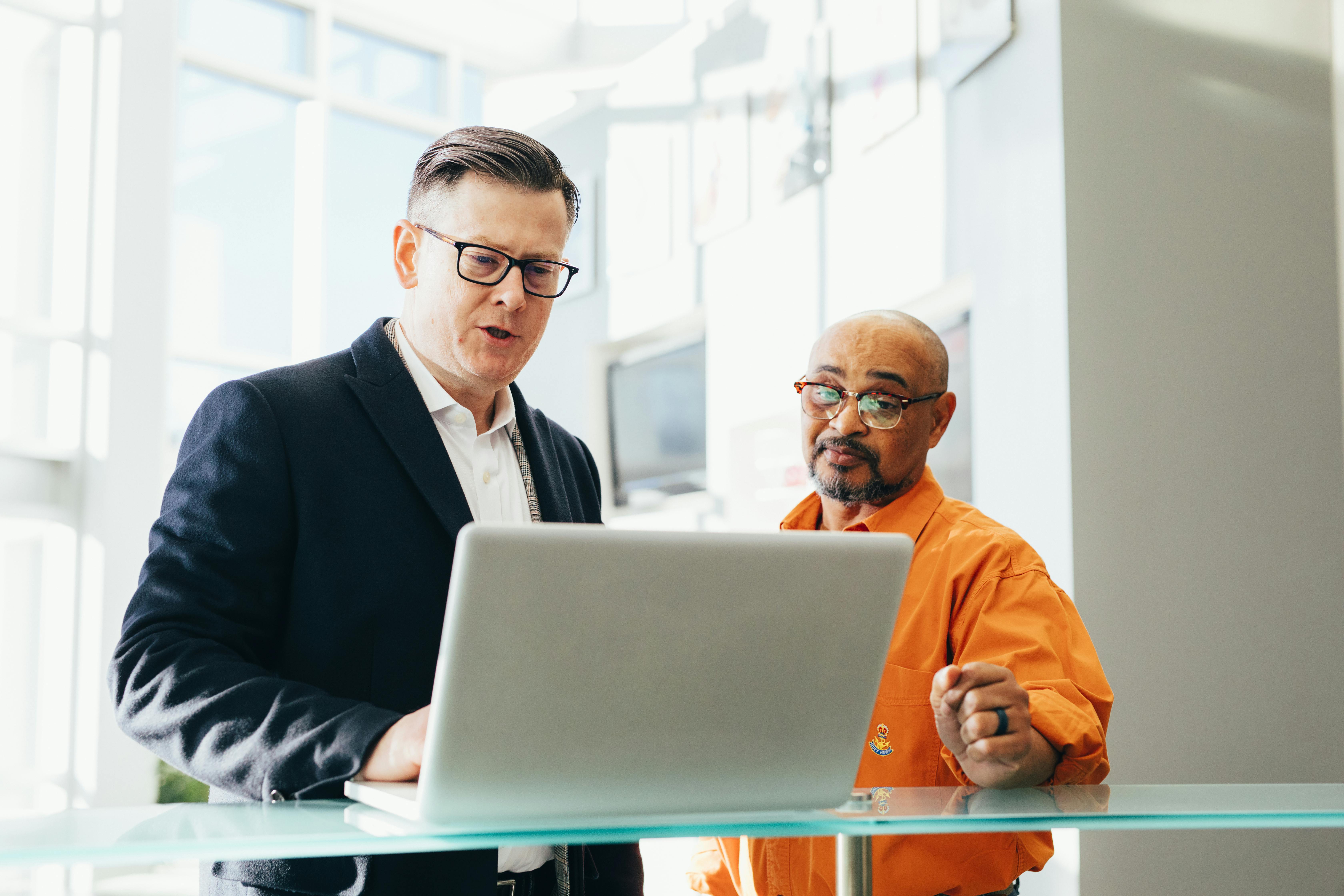 pexels-photo-2182973-2182973 Two business professionals engaged in a collaborative discussion over a laptop in a modern office setting.