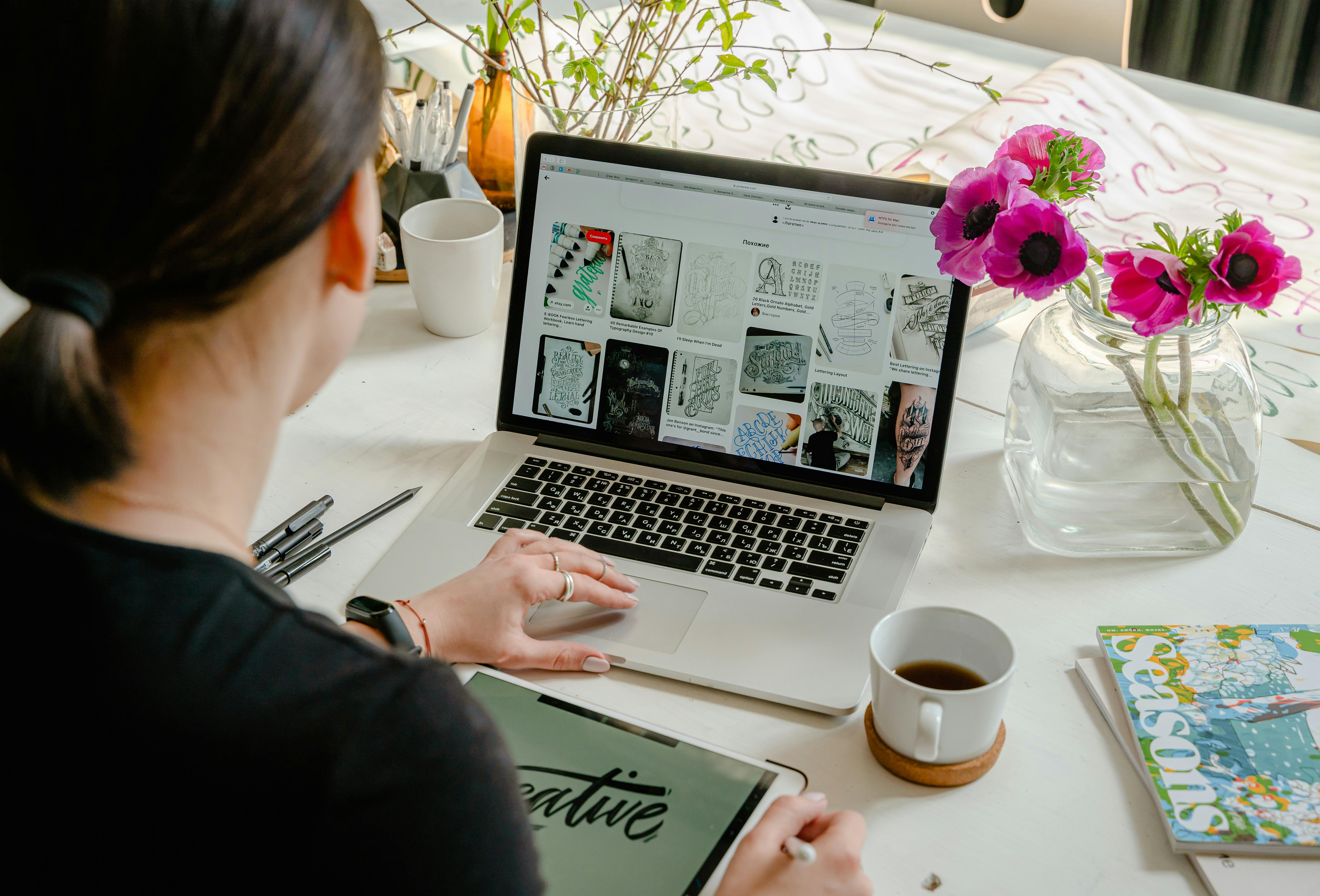 pexels-photo-4348404-4348404 Woman in a creative workspace using a laptop and tablet for calligraphy. Artistic and tech-driven environment.